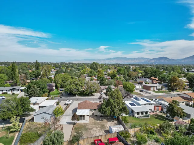 Expansive neighborhood with diverse residential structures, abundant mature trees, and distant mountain scenery