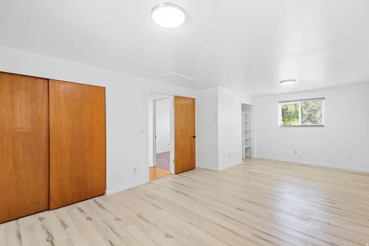 Wood-finish flooring, recessed lighting, built-in shelving, wood panel closet doors, and a natural light window