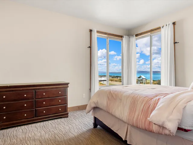 Large corner windows framing a water and sky backdrop, light-colored walls, and textured carpeting