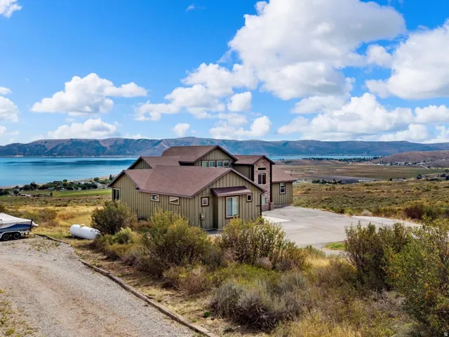 Expansive property featuring a multi-level residence with a brown shingle roof and a spacious asphalt driveway