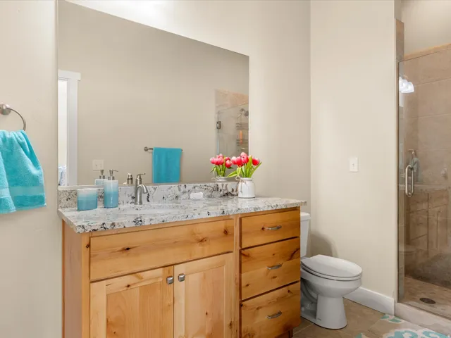 Wood-finish vanity with a light-toned countertop, undermount sink, and brushed nickel faucet