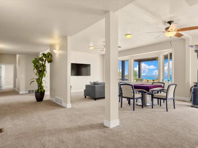 Expansive carpeted area with recessed lighting, ceiling fans, and a bay window