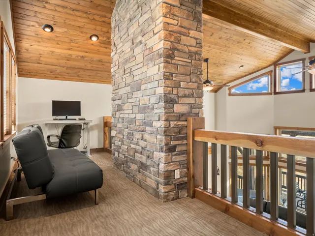 Vaulted wood-paneled ceiling, stone column, wood and metal railing, and high triangular windows