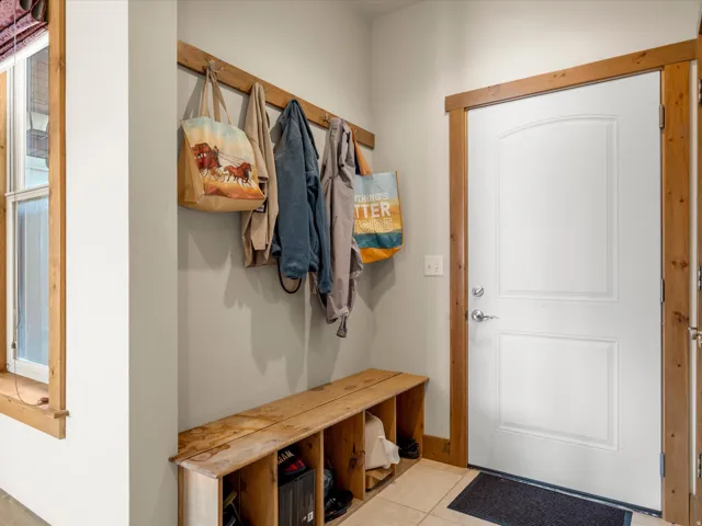 Entryway featuring a built-in wood bench with storage cubbies, a wood coat rack, and a paneled white door with wood trim