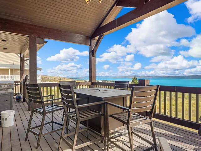 Covered outdoor deck with wooden decking, wood-toned support beams, and a surrounding railing