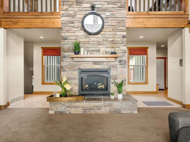 Stone-clad fireplace with a raised hearth, wood mantel, and integrated gas insert