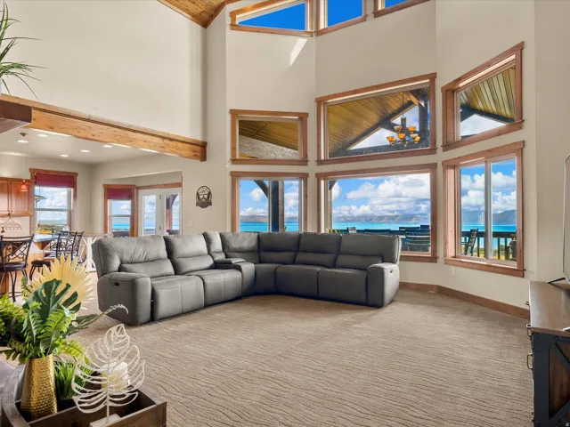 Vaulted ceilings with exposed wood beams, extensive floor-to-ceiling windows, and wood-trimmed window frames