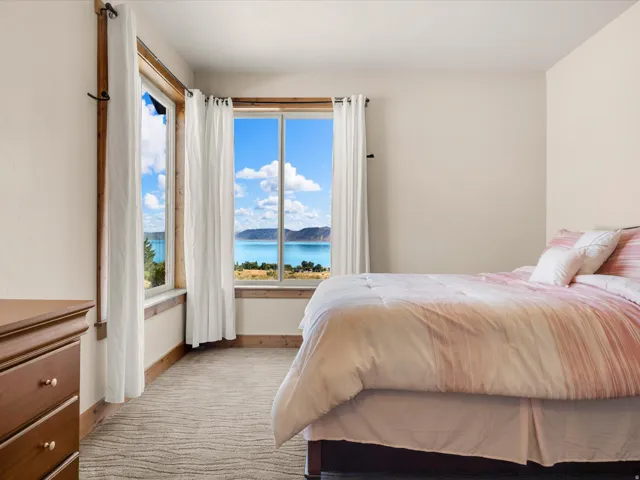 Expansive window arrangement with lake and mountain scenery, natural wood window trim, and neutral wall tones