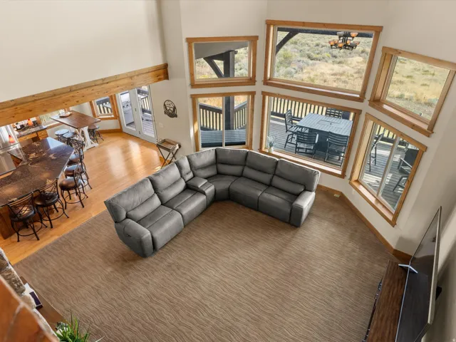 Vaulted ceilings with exposed wood beam, natural wood-framed windows, wood-finish flooring, built-in kitchen island with countertop, and outdoor deck