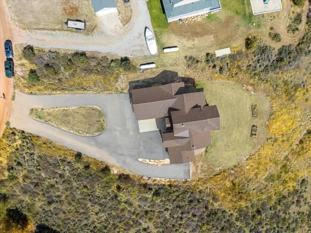 Expansive lot with a multi-level roofline, extensive paved driveway, and natural landscaping