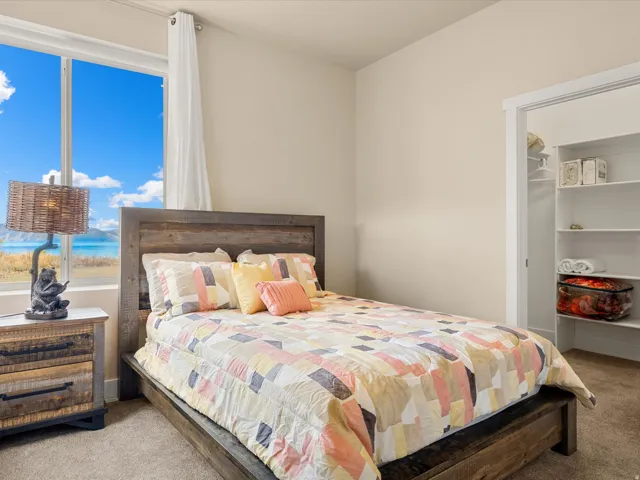 Window with scenic backdrop, wood-finish bed frame, built-in closet shelving, neutral wall paint, and carpet flooring