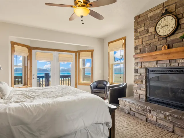 Stone-clad fireplace with a wood mantle, French doors, and bay windows