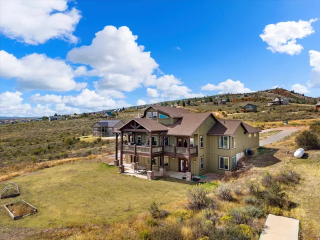 Multi-level residence featuring a prominent covered porch, an expansive lower-level patio, and a pitched roofline