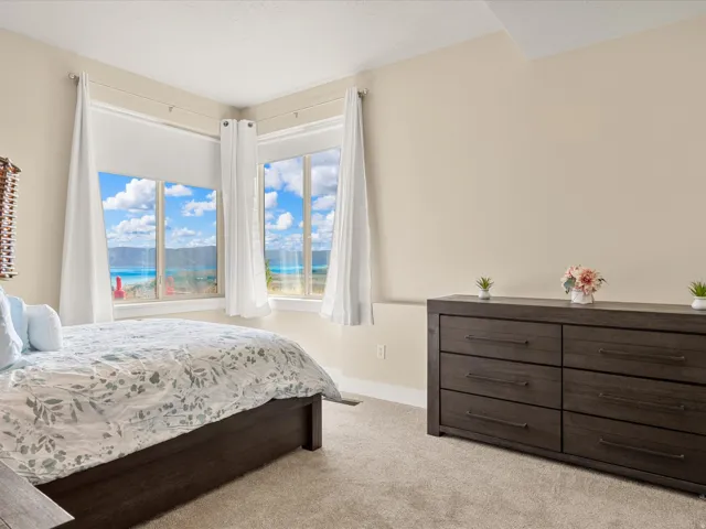 Expansive windows showcasing a water and mountain backdrop, complemented by neutral wall tones and plush carpeting