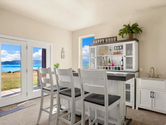 Built-in bar with seating for three, integrated shelving, and glass-front cabinets