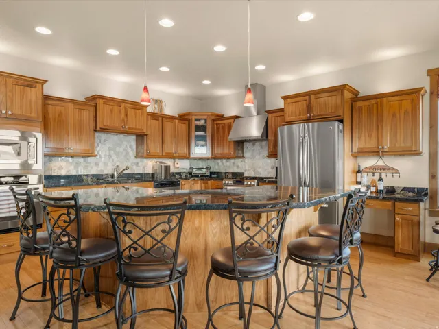 Kitchen featuring wood cabinetry, stainless steel appliances, dark stone countertops, and a tiled backsplash