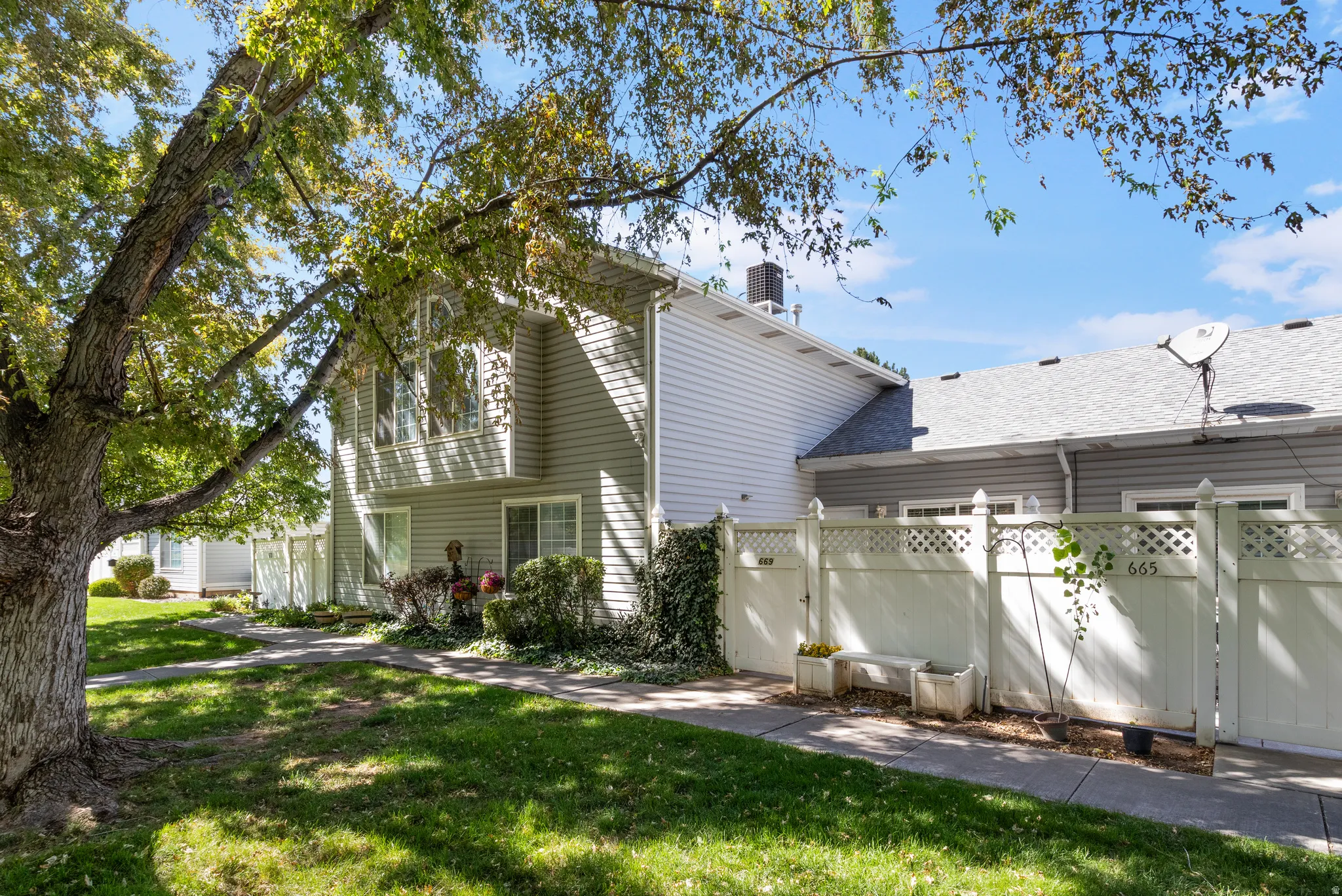 Two-story exterior with siding, bay window, and white lattice fencing