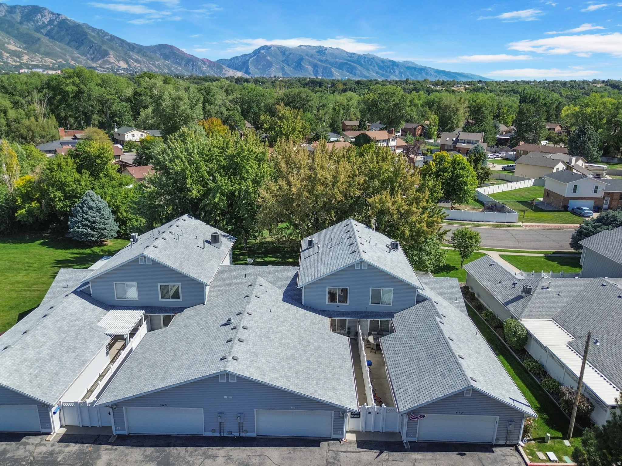 Multi-unit residential structure featuring attached garages, gabled roofs with asphalt shingles, and light blue siding