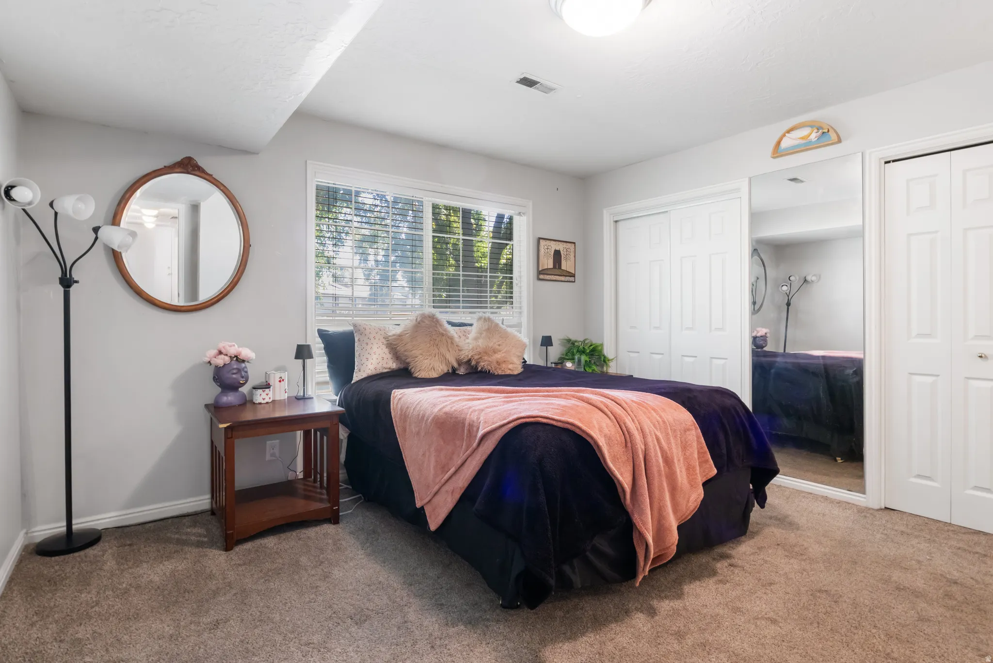 Wall-to-wall carpeting, window with blinds, bi-fold closet doors, sliding mirrored closet door, and a flush-mount ceiling light fixture