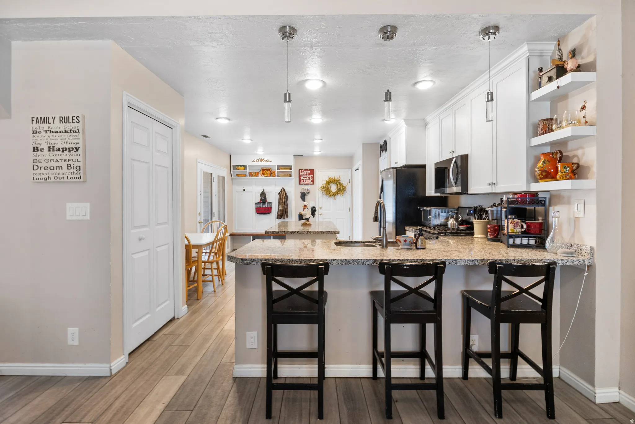 Kitchen featuring granite countertops, white cabinetry, stainless steel appliances, wood-finish flooring, and recessed lighting