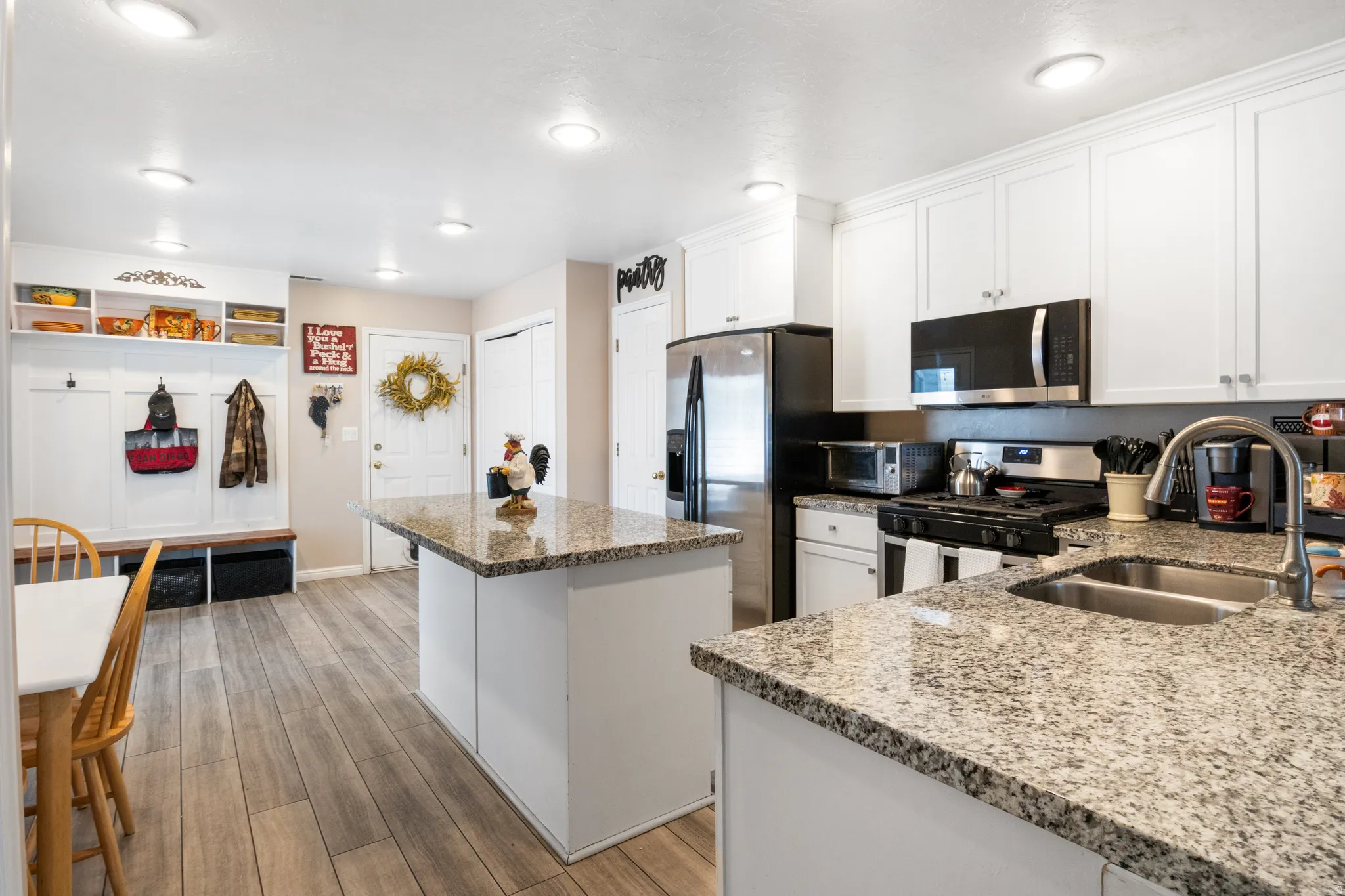 Kitchen featuring granite countertops, white cabinetry, stainless steel appliances, and wood-finish flooring