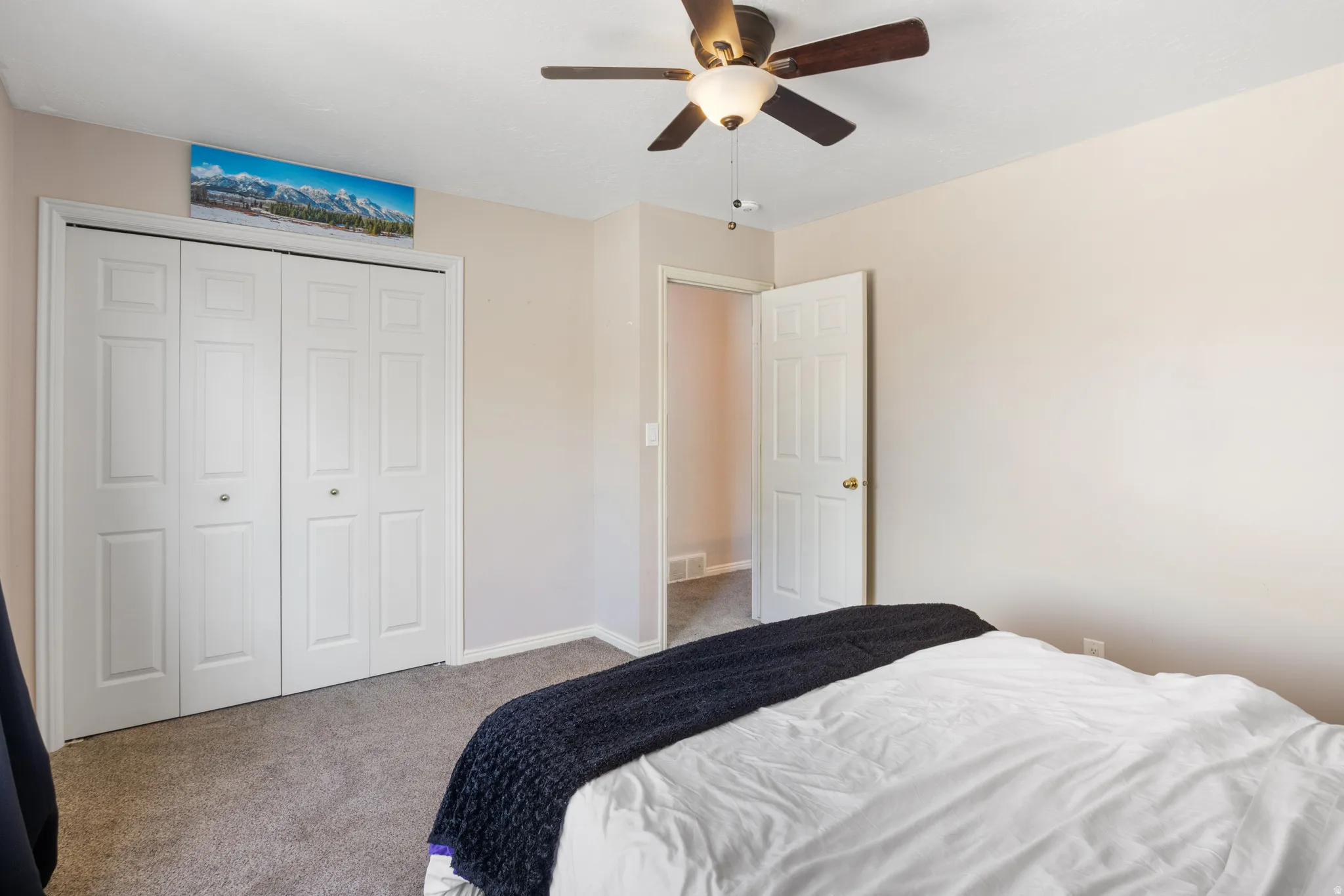 Carpeted flooring, bi-fold closet doors, ceiling fan with integrated lighting, and painted walls