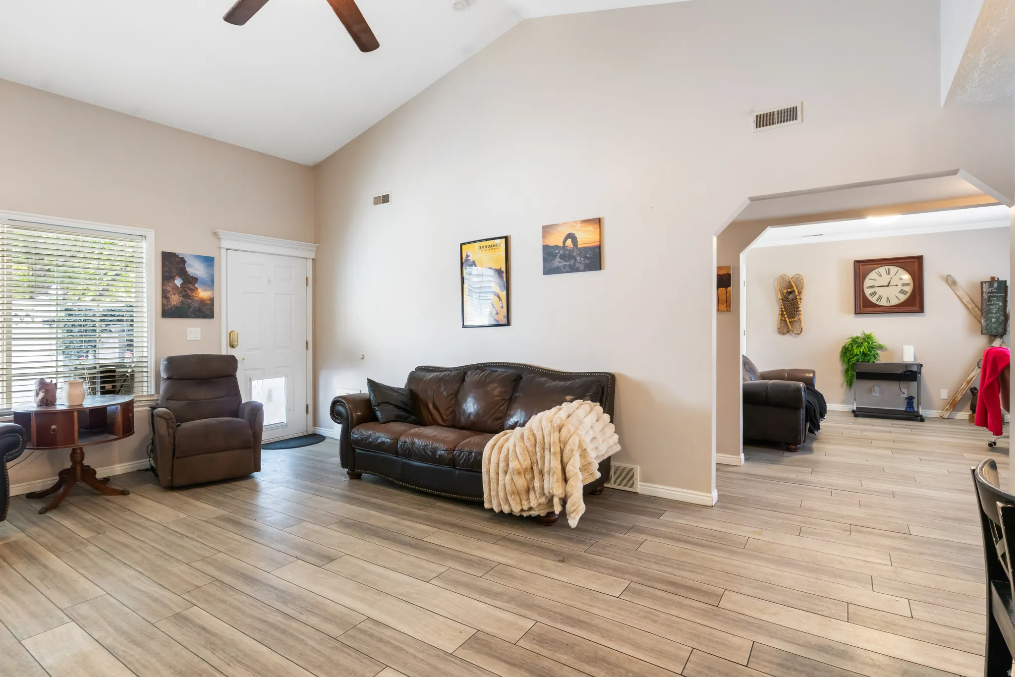 Vaulted ceiling, wood-finish flooring, ceiling fan, arched doorway, and white trim throughout