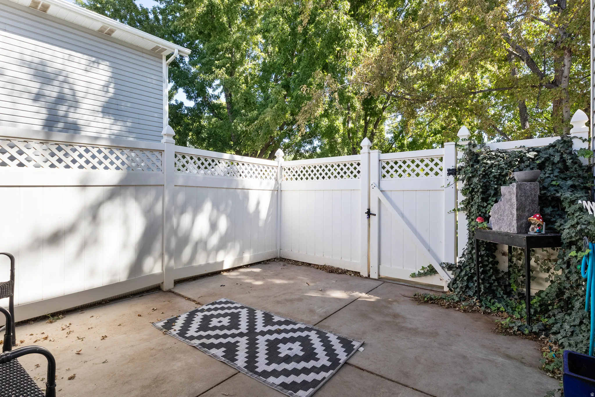 Enclosed concrete patio with a white lattice-top privacy fence and a gated entry