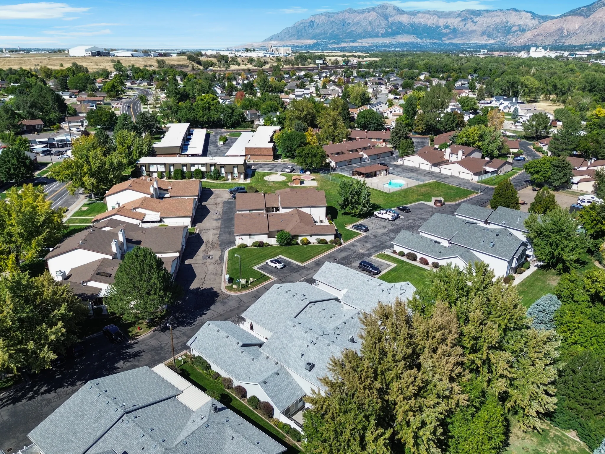 Community with multiple residential buildings, paved parking areas, and mature landscaping
