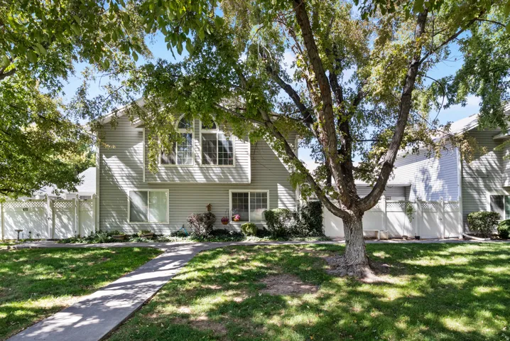 Two-story exterior with horizontal siding, arched window, mature trees, and a concrete pathway