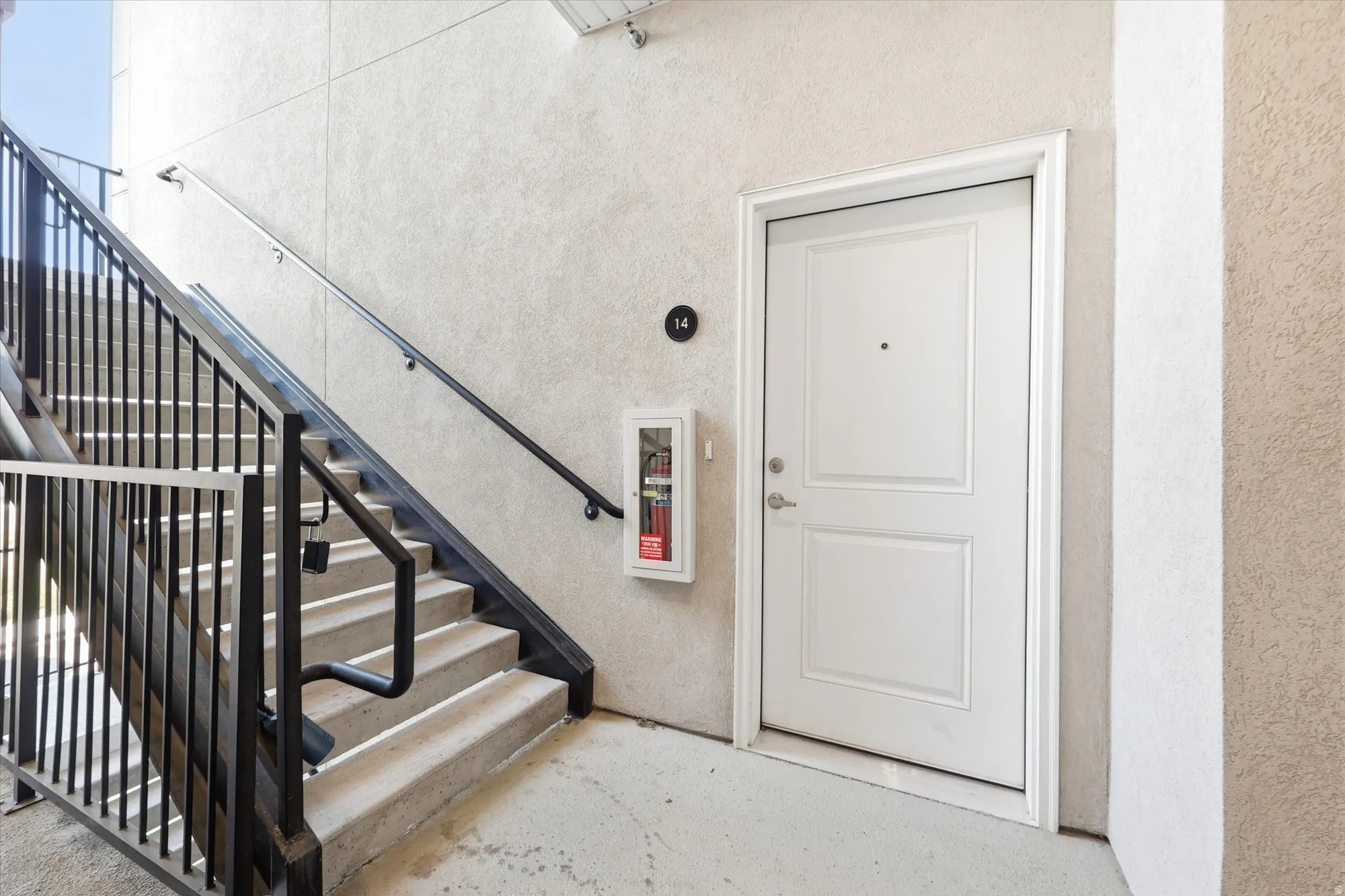 Concrete stairwell with black metal railings and a white panel door