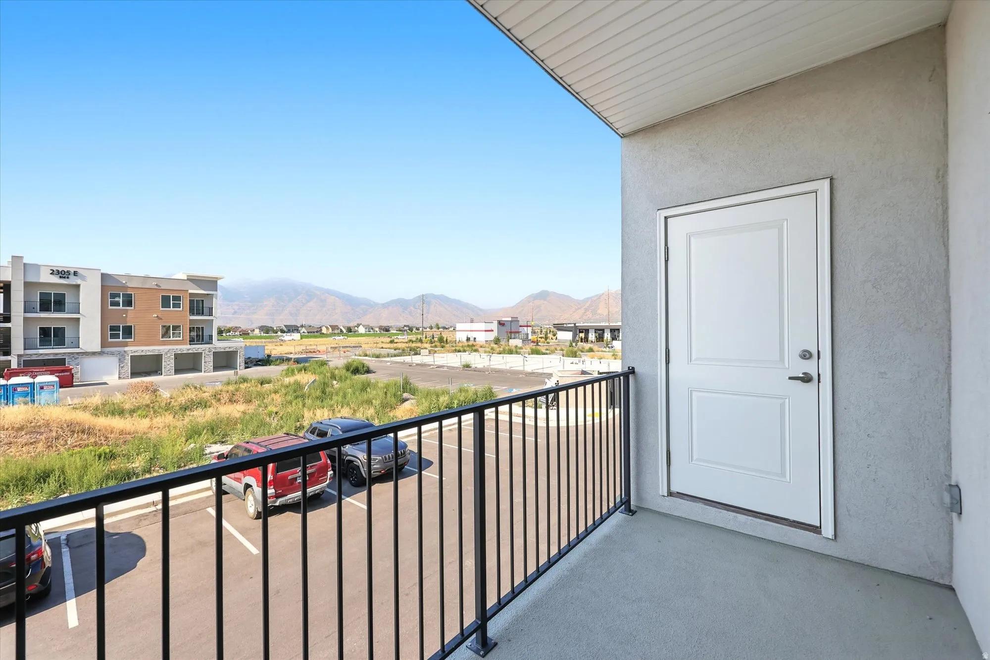 Balcony with concrete flooring, black metal railing, and a white paneled door