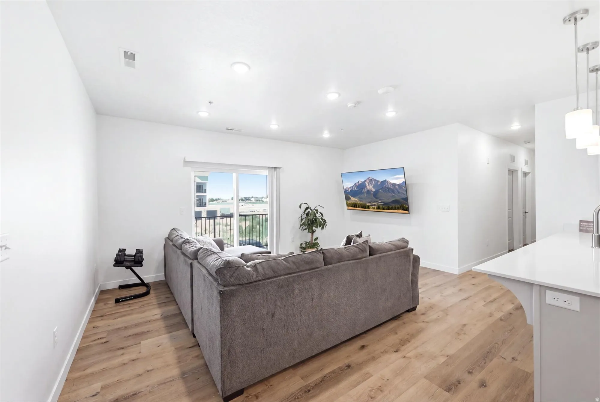 Wood-finish flooring throughout, recessed lighting, and a sliding glass door