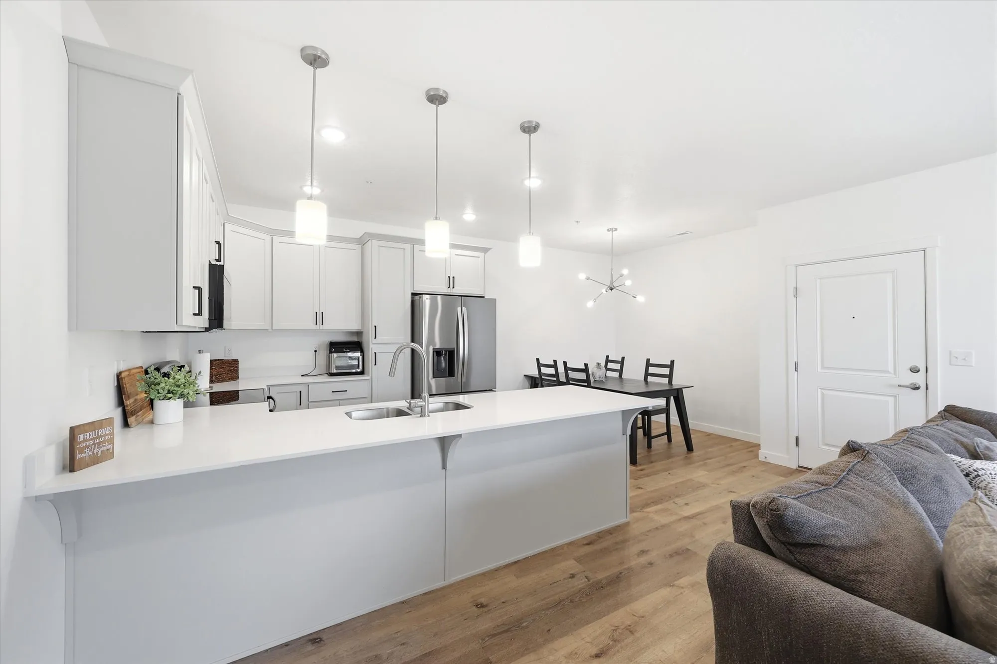 Open-concept kitchen featuring white cabinetry, light-toned countertops, and stainless steel appliances