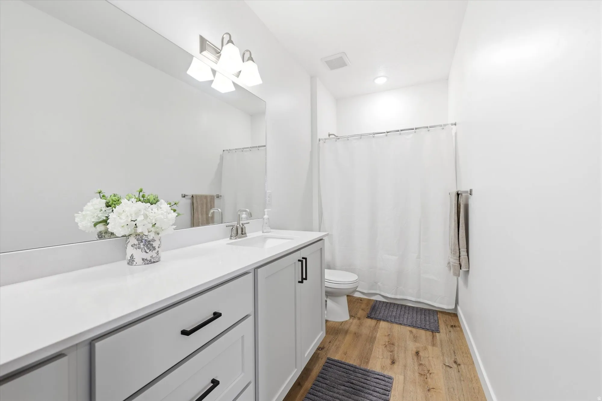 Bathroom featuring a light gray vanity with black hardware, white countertop, and an undermount sink