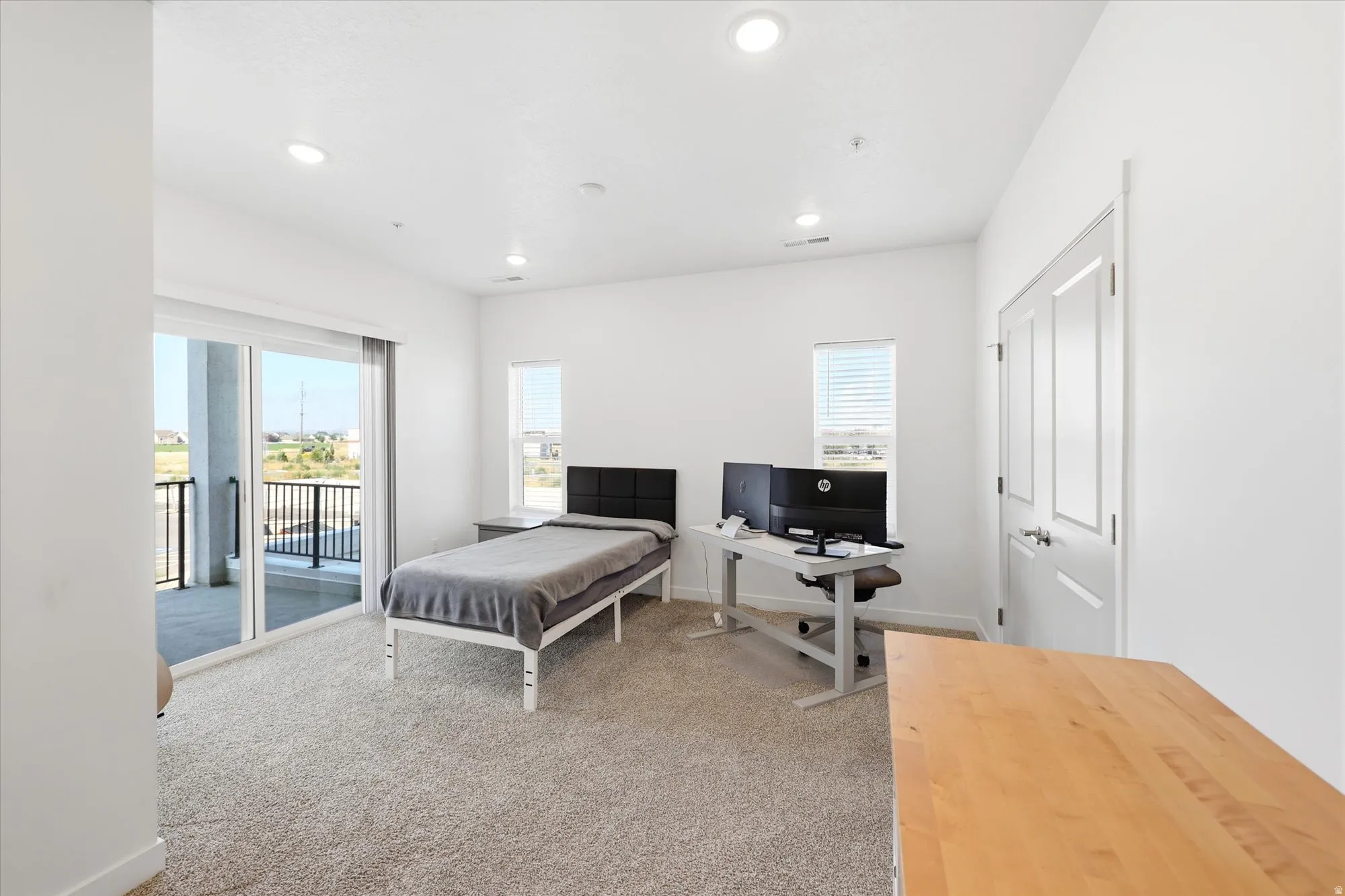 Plush carpet flooring, recessed ceiling lighting, sliding glass door access to a private balcony, and painted paneled doors