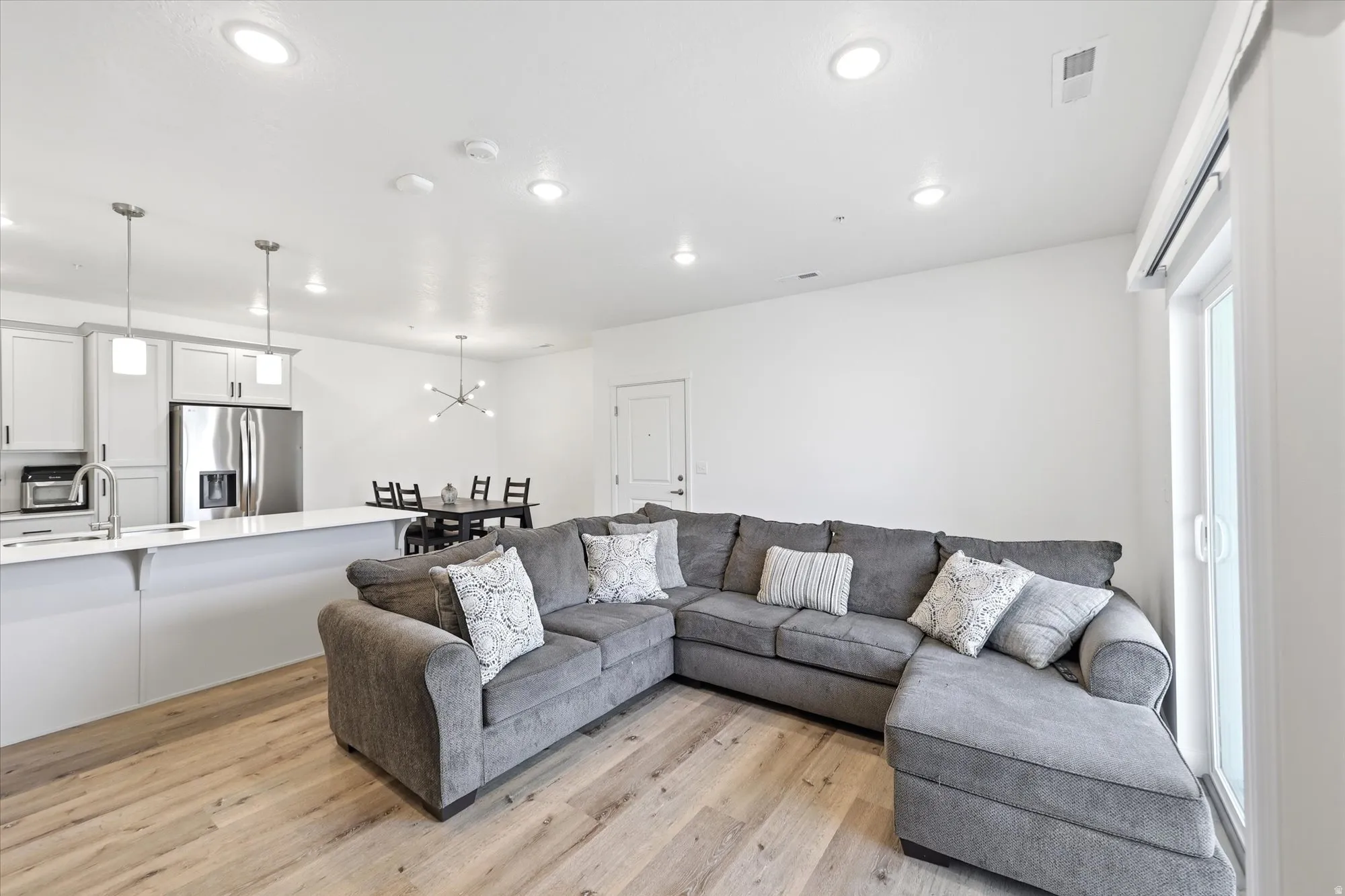 Open-concept living area with wood-finish flooring, recessed lighting, and a sliding glass door