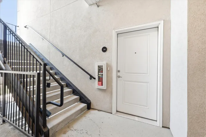 Concrete stairwell with black metal railings and a white panel door