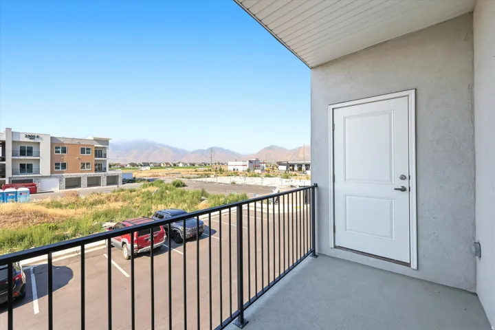 Balcony with concrete flooring, black metal railing, and a white paneled door