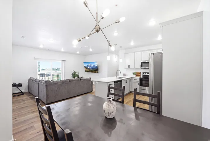 Open-concept living space featuring wood-finish flooring, recessed lighting, and a sliding glass door to a balcony