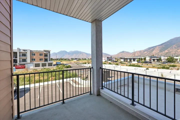 Outdoor balcony with concrete flooring, black metal railing, and a slatted ceiling
