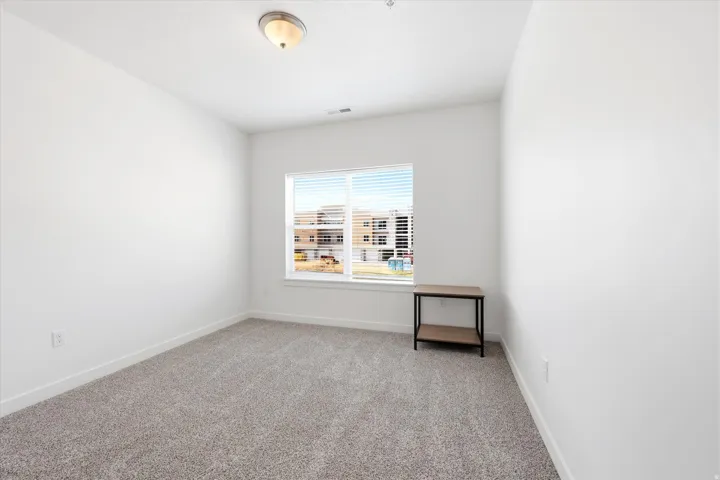 Neutral carpet flooring, white walls, and a window with blinds