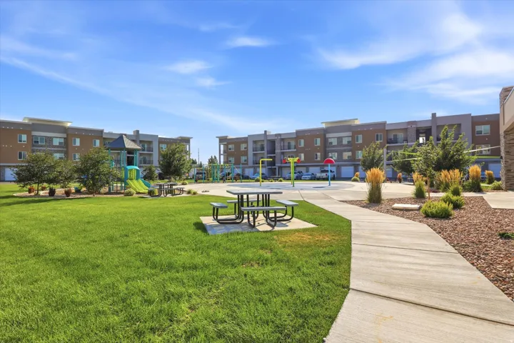 Expansive green space featuring a playground, picnic seating, and a concrete pathway