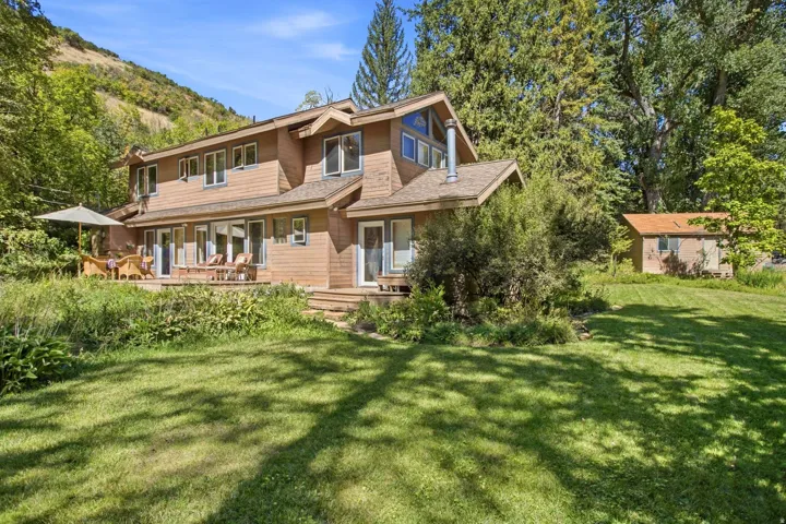 Wood-sided exterior featuring multiple windows, a rear deck, and a detached outbuilding