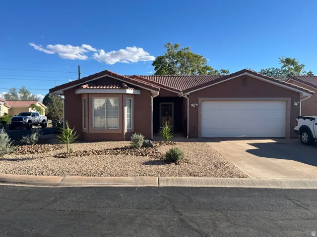 Stucco exterior with a tiled roof, integrated two-car garage, and a bay window