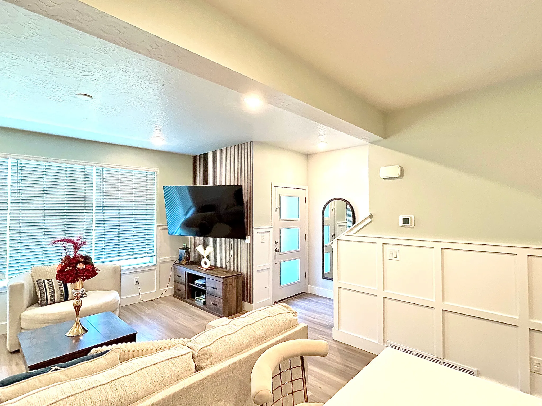 Recessed lighting, wood-finish flooring, accent wall paneling, white interior door with frosted glass panels, and board and batten wall details