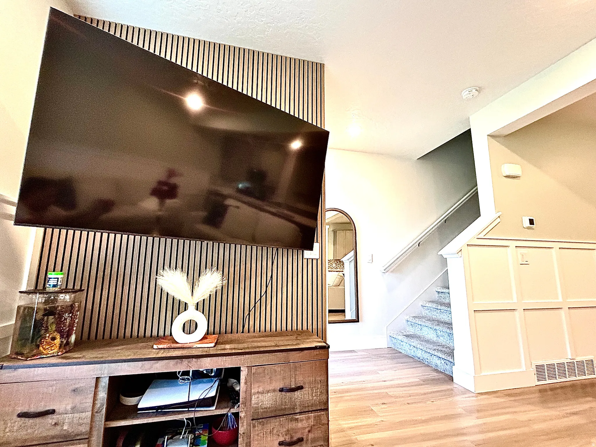Accent wall with vertical wood paneling, wood-finish flooring, and wainscoting