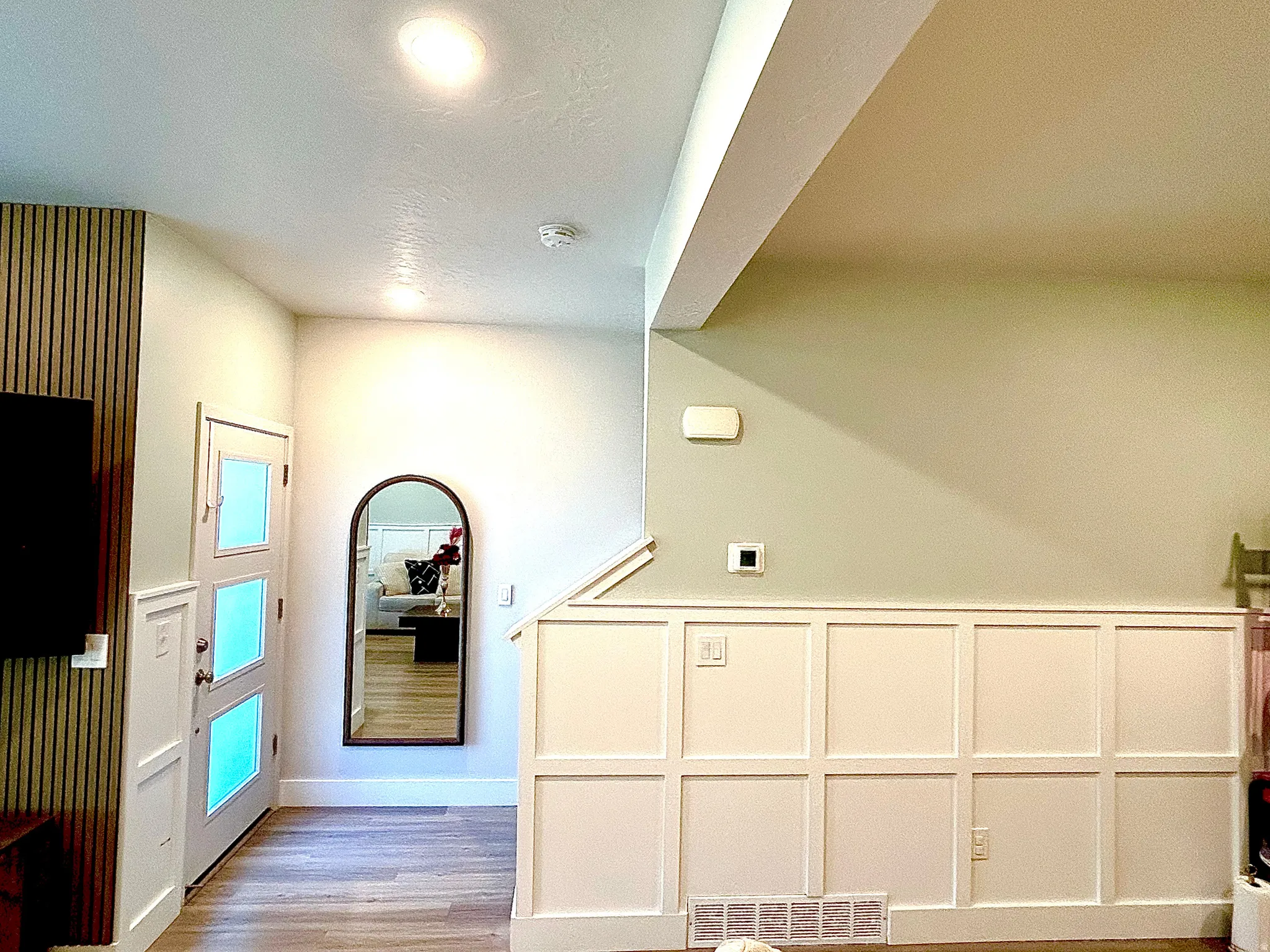 Wood-finish flooring, recessed lighting, white paneled wainscoting, and a multi-paneled door