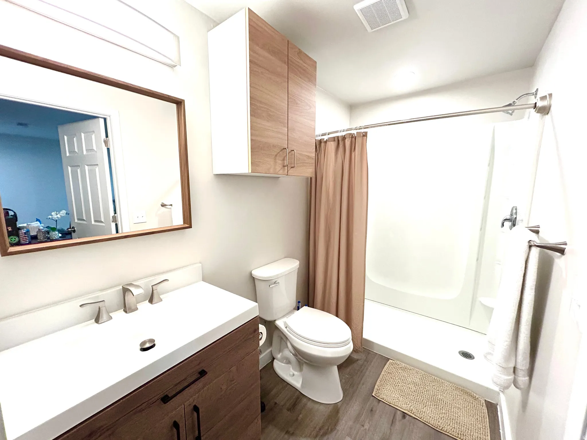 Wood-finish vanity with a white countertop and brushed nickel faucet