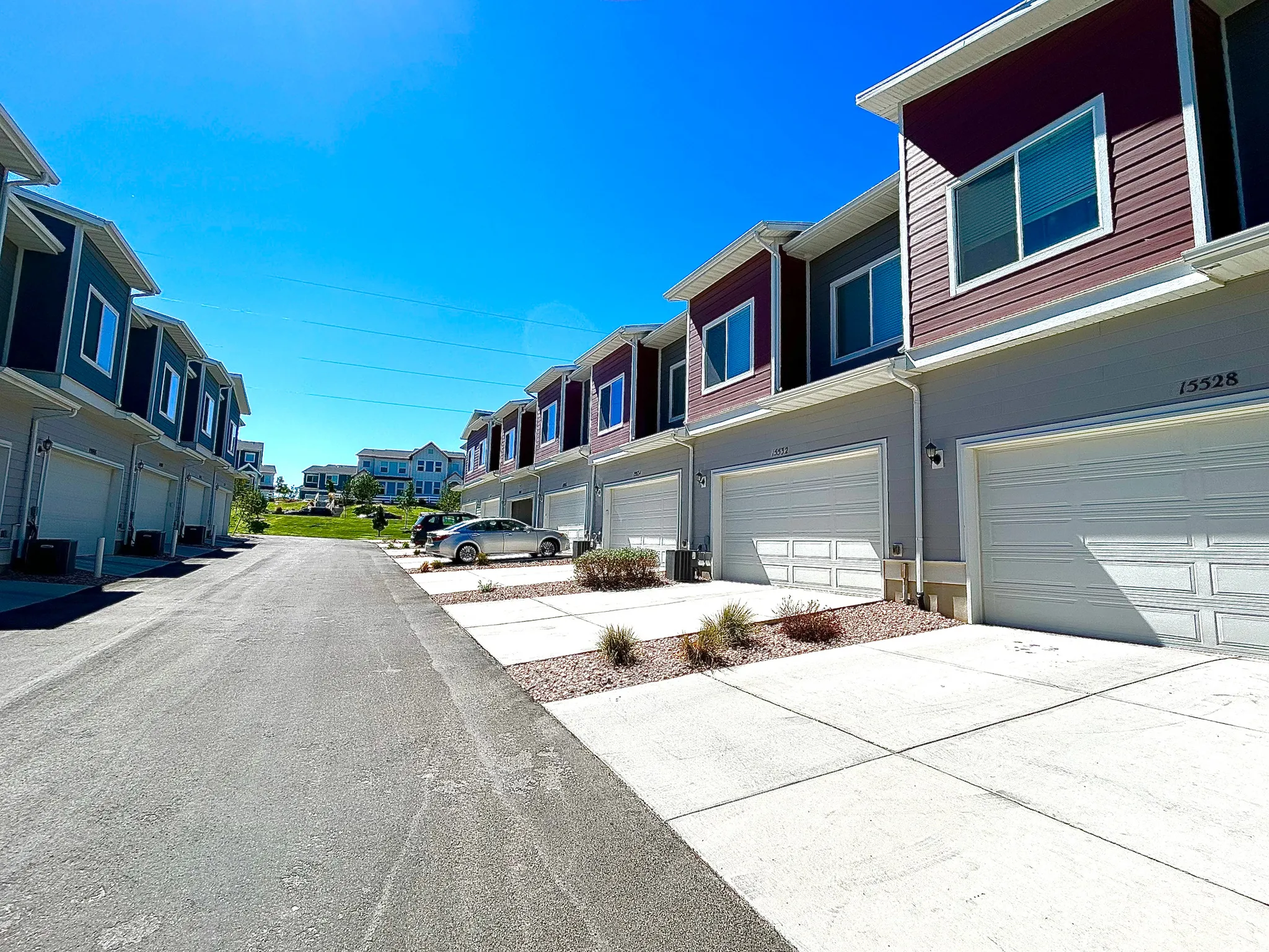 Contemporary townhome exterior with contrasting siding, individual garage access, and a concrete driveway